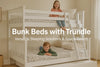 White wooden bunk bed with trundle in a bright kids' room, showing two happy children and a space-saving design

